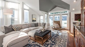 A spacious living room with a large sectional sofa, a wooden coffee table, and a cozy reading nook.