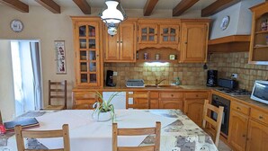Una cocina con armarios de madera, una mesa de comedor con sillas, una lámpara colgante y salpicadero de azulejos.