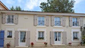 Un edificio de varios pisos con fachada color beige, contraventanas blancas y numerosas ventanas con rejas de hierro decorativas.