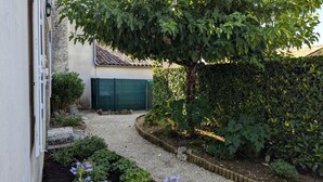 A garden pathway leading to a house with a tiled roof and a green door. - Charming Cottage with Pool, Fireplace, and Garden in Vineyard Estate (Saint-Cybardeaux)