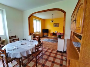 A dining area with a table set for four, a television, and a wooden cabinet.