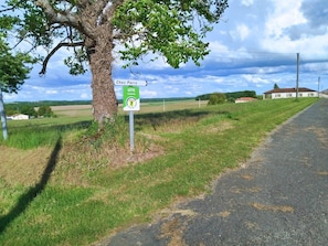Une route de campagne avec un panneau indiquant « Chez Perry » et un panneau « Gîte Charente ».