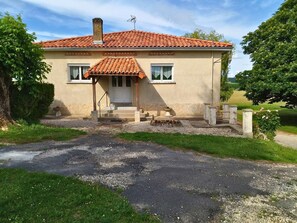 Ein zweistöckiges Haus mit rotem Ziegeldach, Schornstein und einer Veranda mit Stufen zum Eingang.