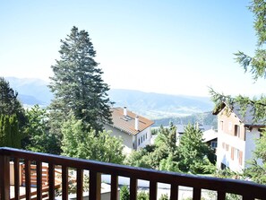 A residential area with a view of distant mountains, surrounded by trees and houses with red-tiled roofs. - Charming south-facing 2-room near center with parking in Font-Romeu (Font-Romeu-Odeillo-Via)