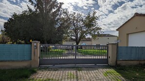 Een poort leidt naar een oprit van tegels die naar een gebouw met een pannendak voert.