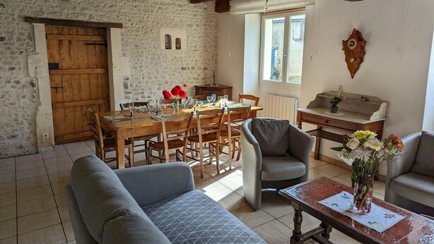 Een rustieke kamer met een stenen muur, houten meubels, een eettafel en een bank.