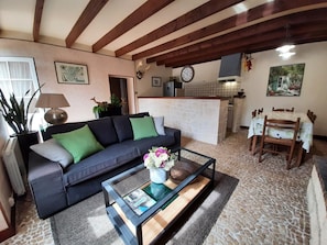 Un salon comprenant un canapé, une table basse avec un magazine, une lampe, ainsi qu’un coin repas avec une table et des chaises.