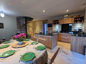 Une cuisine moderne avec des meubles en bois, un îlot central intégré et un escalier en colimaçon.