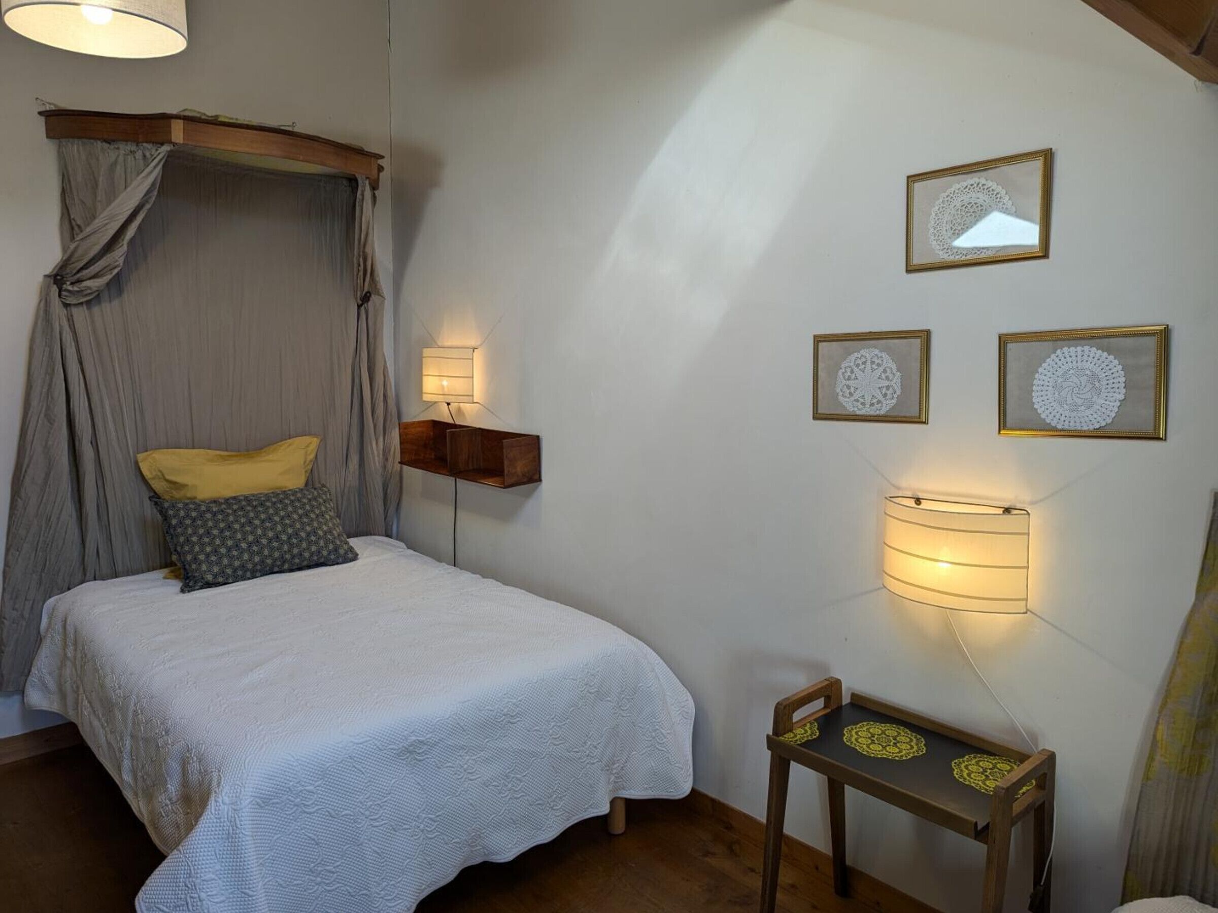 A bedroom with a canopy bed, bedside lamps, and framed wall art.