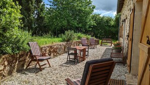 An outdoor patio area with stone walls, wooden furniture, and a gravel floor. - Spacious house in Massignac with private garden (Massignac)