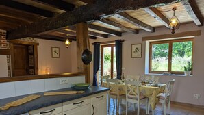 A kitchen with white cabinets, a blue countertop, and a dining area with white chairs and a table. - Spacious house in Massignac with private garden (Massignac)