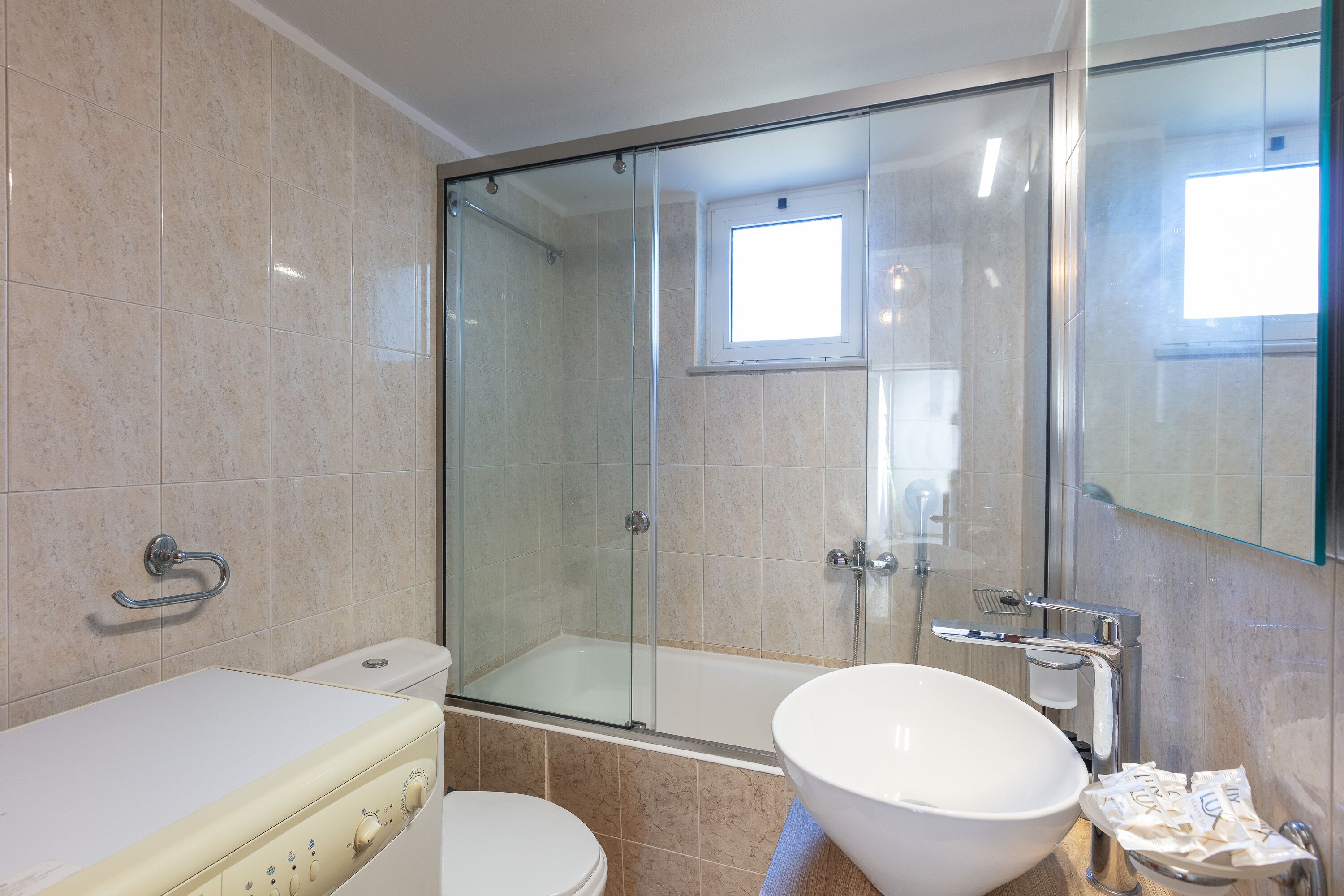 Un baño moderno con ducha de vidrio, un lavabo blanco y un inodoro.