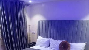 A neatly made bed with a dark headboard, white pillows, and a rolled towel on the bed. - Haven Suite (Lagos)