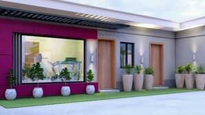 A modern building with a large window, a red facade, and potted plants. - Haven Suite (Lagos)