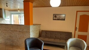 A modern lobby with a stone wall, a grey sofa, two armchairs, and a wooden ceiling. - Renovated Charente cottage with vineyard views, near Angoulême (Champagne-Vigny)