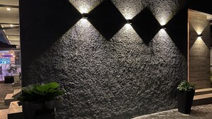 A textured wall with diamond-shaped lighting fixtures and potted plants. - Riivana Leisure Tavern (Lekki)