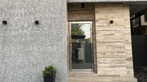 A modern building with a textured facade, a wooden entrance, and a potted plant. - Riivana Leisure Tavern (Lekki)