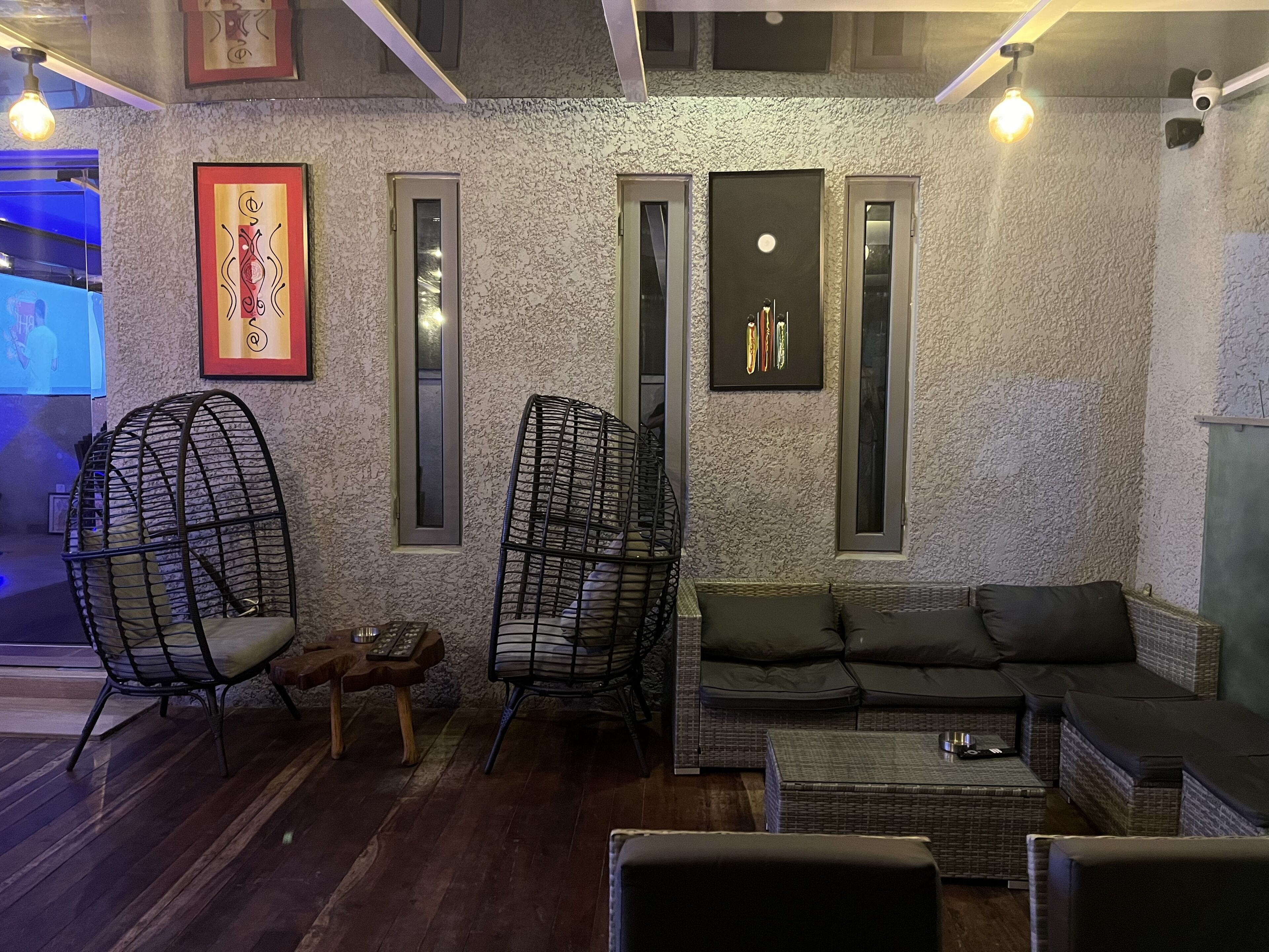 A cozy lounge area with wicker furniture, a cushioned sofa, and a small wooden table.