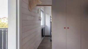 A narrow hallway with wooden walls, a window, and a door with red handles. - Appartement au Pied des Pistes (Arâches-la-Frasse)