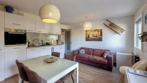 A modern kitchen with white cabinets, a dining table with chairs, and two pendant lights. - Appartement au Pied des Pistes (Arâches-la-Frasse)