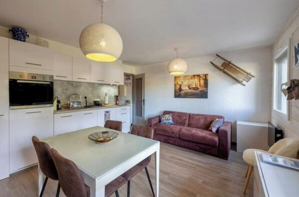 A modern kitchen with white cabinets, a dining table with chairs, and two pendant lights.