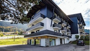 A multi-story hotel with balconies, a visible restaurant, and a mountainous backdrop. - Appartement au Pied des Pistes (Arâches-la-Frasse)