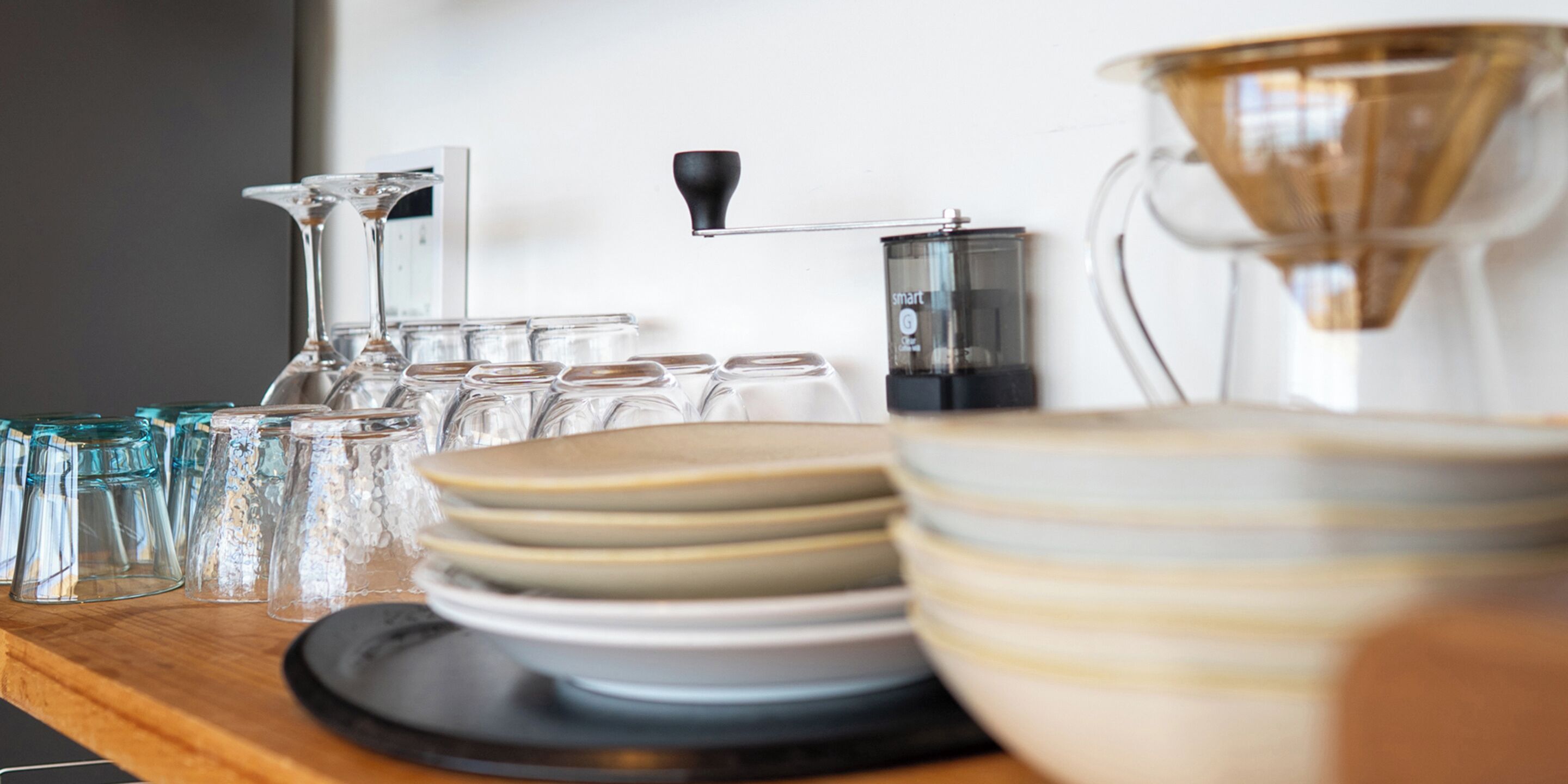A kitchen counter with various glassware, plates, and a coffee maker.