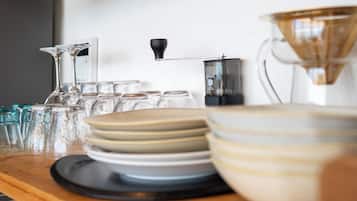 A kitchen counter with various glassware, plates, and a coffee maker.