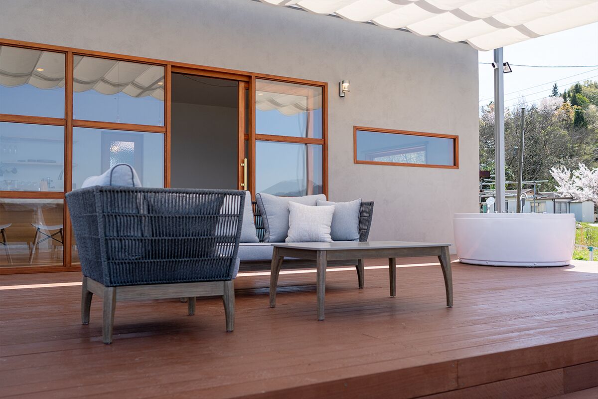 Un espace extérieur moderne aménagé avec un canapé, une table et un grand bac à plantes.
