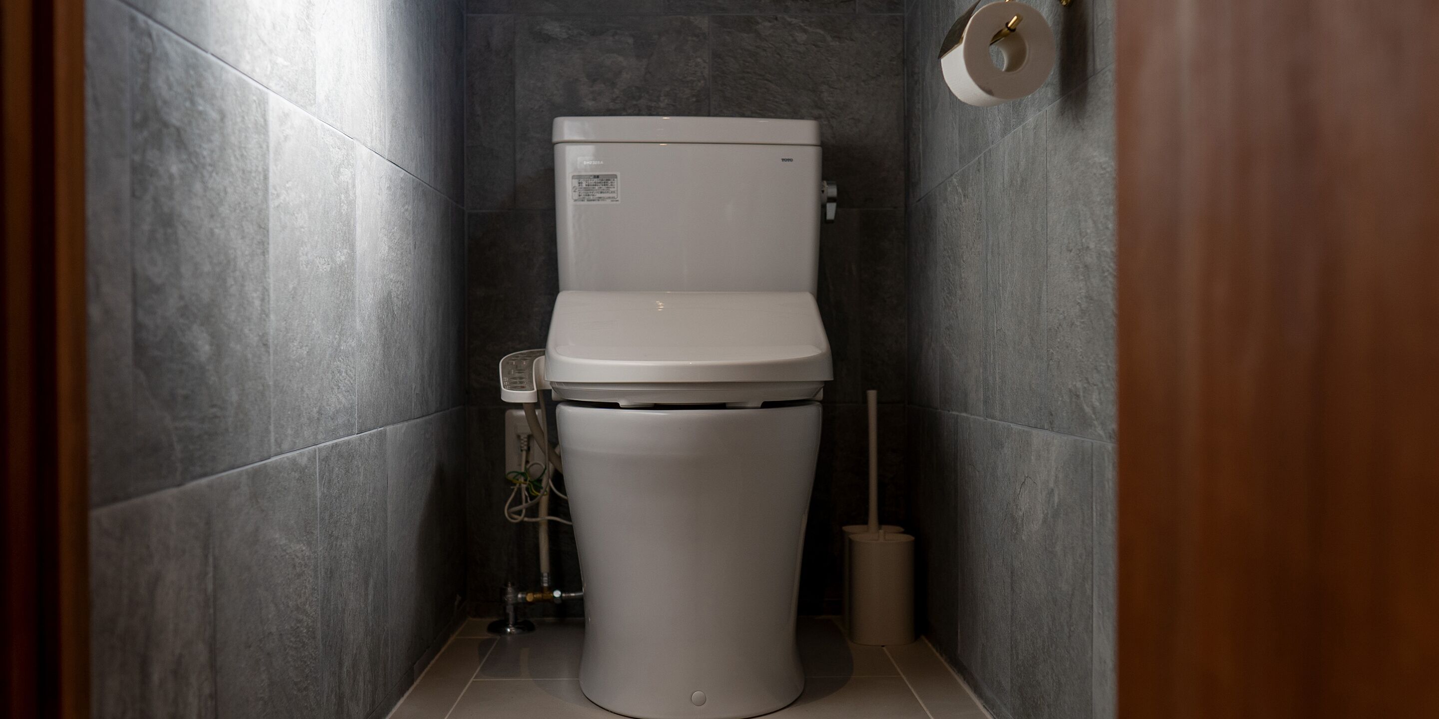 A modern bathroom with a white toilet, a toilet paper holder, and a bidet.