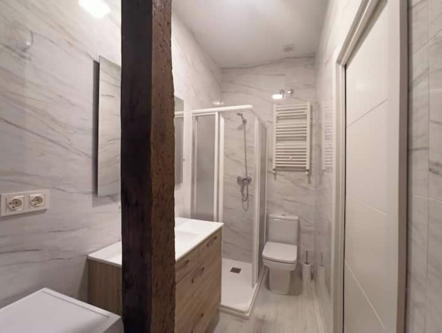 Une salle de bain moderne avec un meuble-lavabo en bois, une cabine de douche en verre et des toilettes.