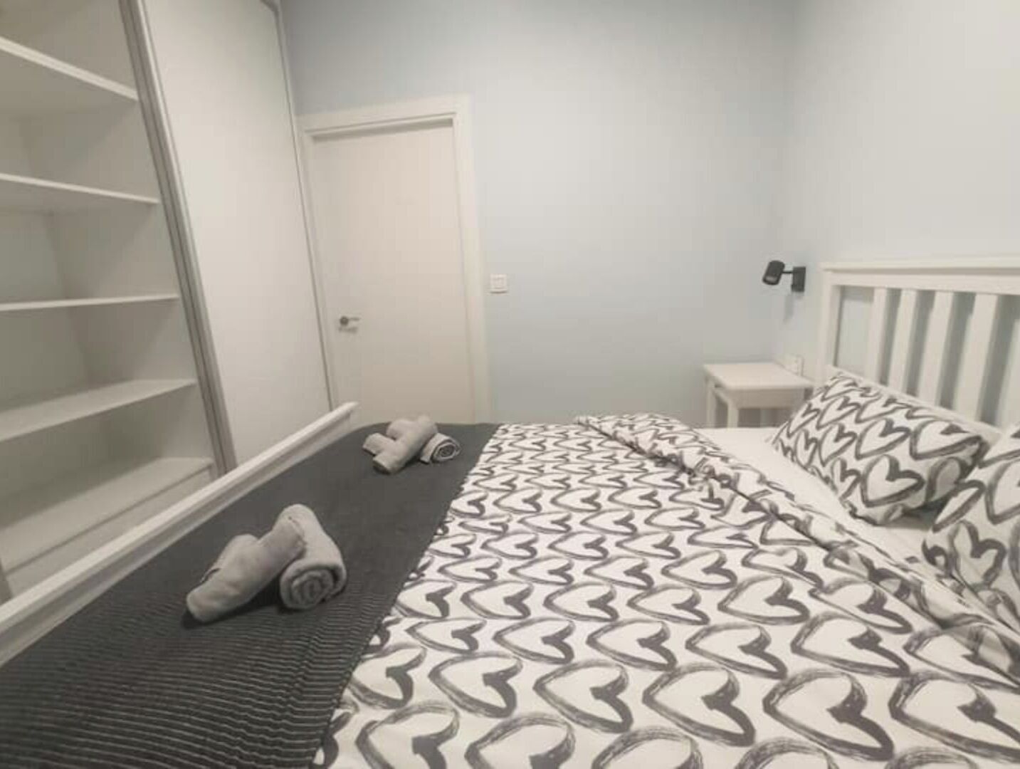 Une chambre à coucher avec un lit, une armoire et une petite table de chevet.