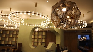 A modern interior with a central seating area, a patterned ceiling light, and a view of the outdoors.