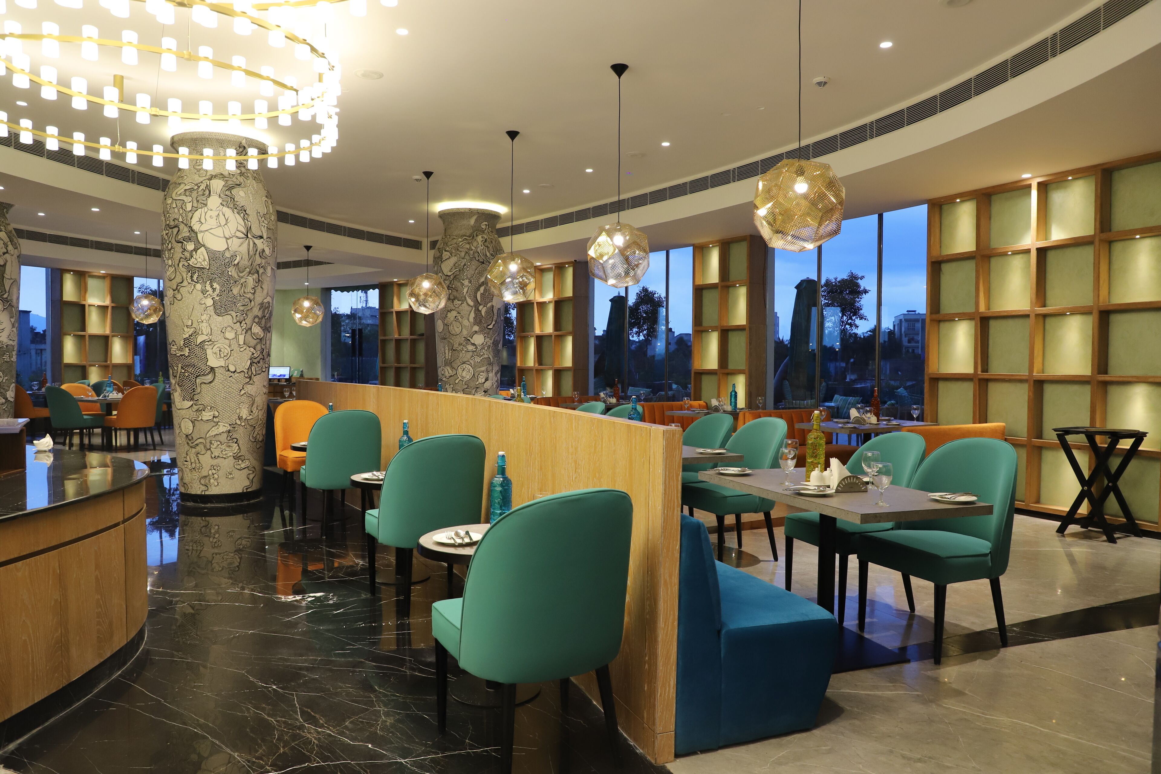A modern restaurant with teal chairs, marble floors, and large windows with city views.