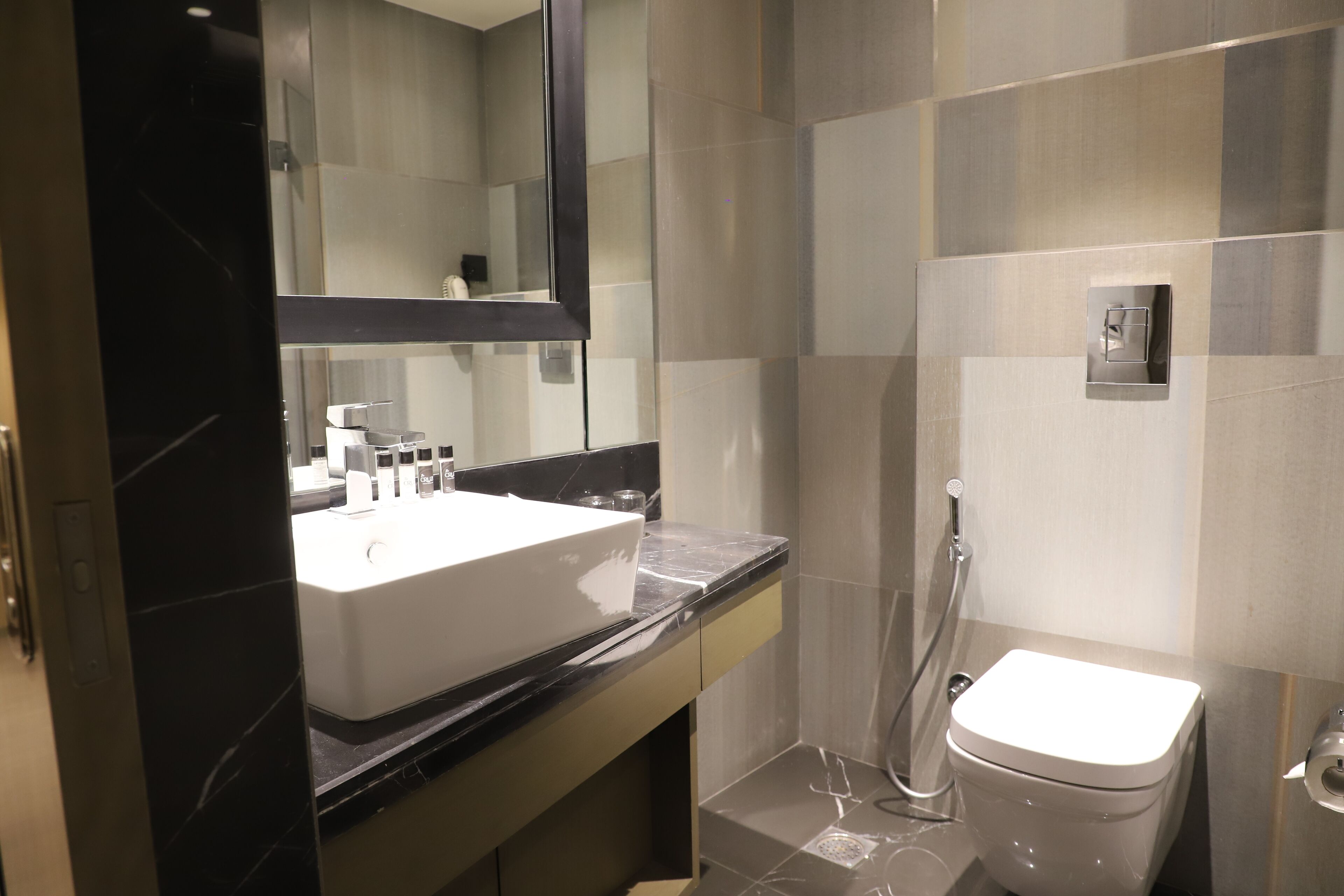 A modern bathroom with a large mirror, a white sink, a toilet, and a shower area.