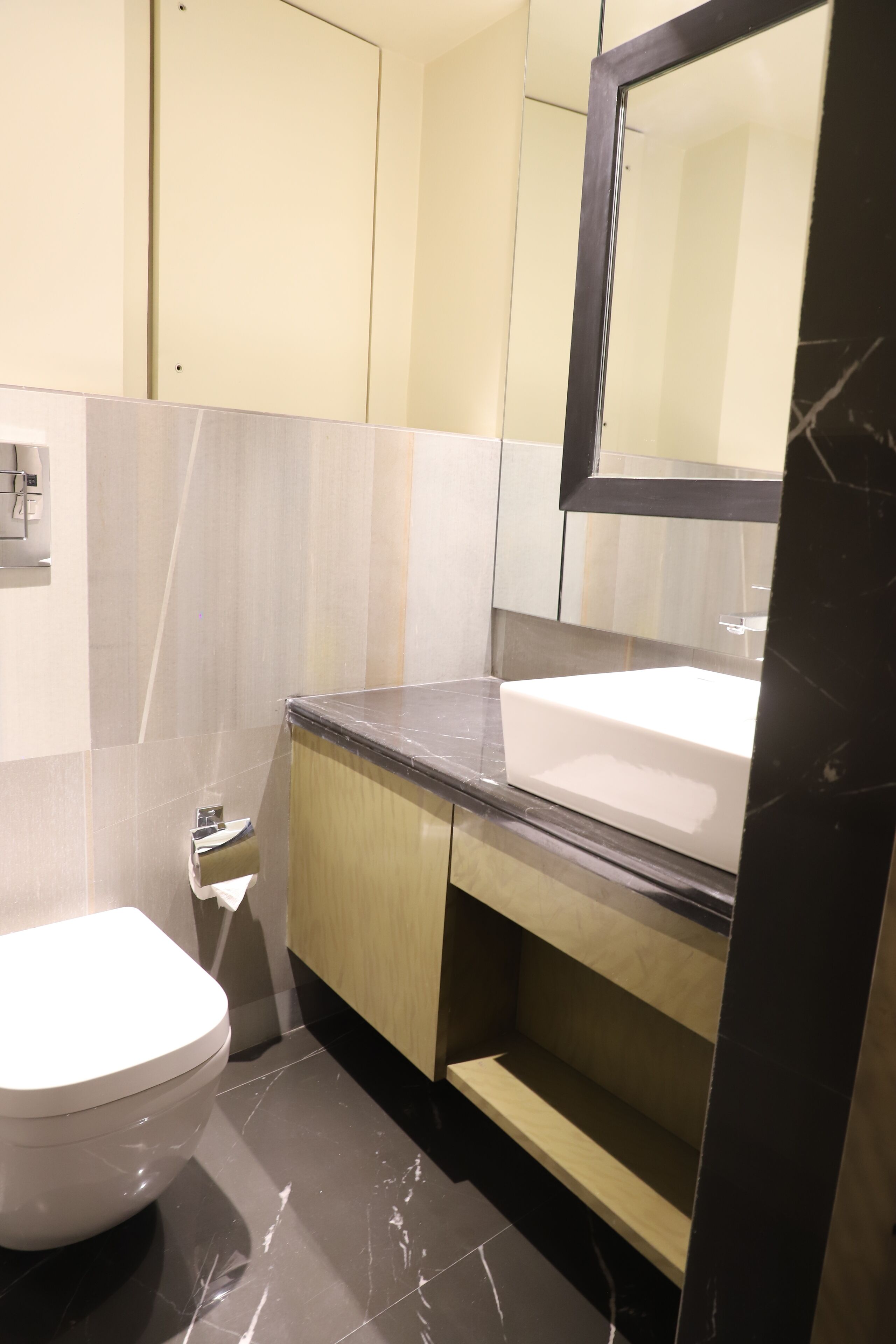 Un baño moderno con inodoro blanco, lavamanos y espejo.