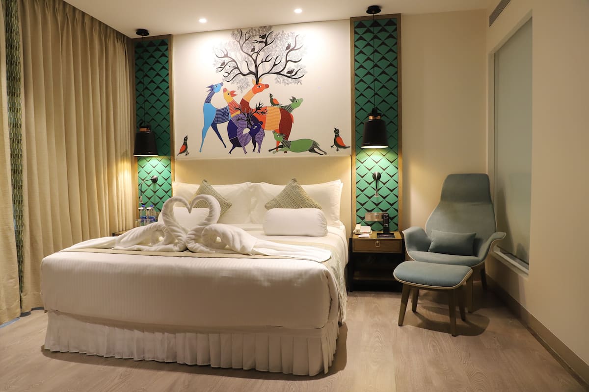 Un dormitorio con una cama grande, una silla, una mesita de noche y un mural en la pared.