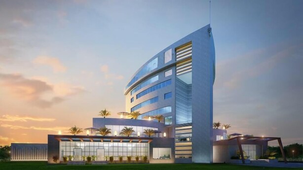 A modern hotel with a curved facade, multiple floors, and a prominent antenna.