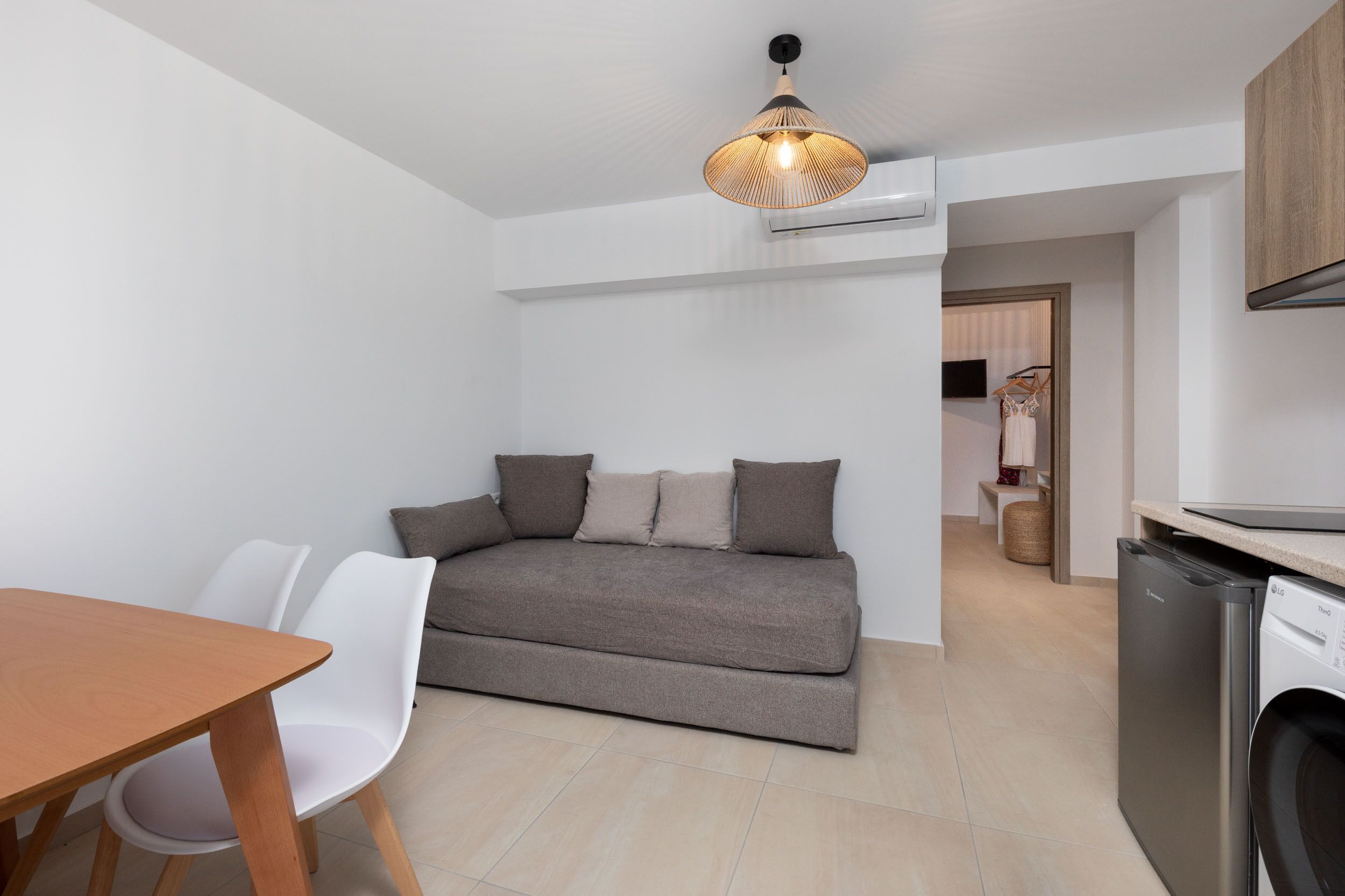 Un espacio habitable pequeño con un sofá, una mesa de comedor y una lavadora.