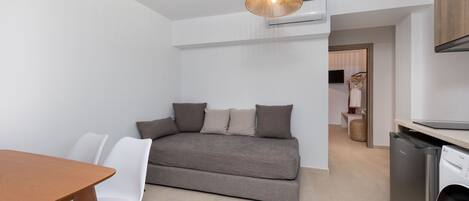 Un espacio habitable pequeño con un sofá, una mesa de comedor y una lavadora.
