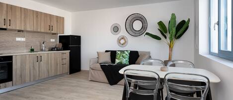 A modern kitchen with wooden cabinets, a dining area with a table and chairs, and a large plant.
