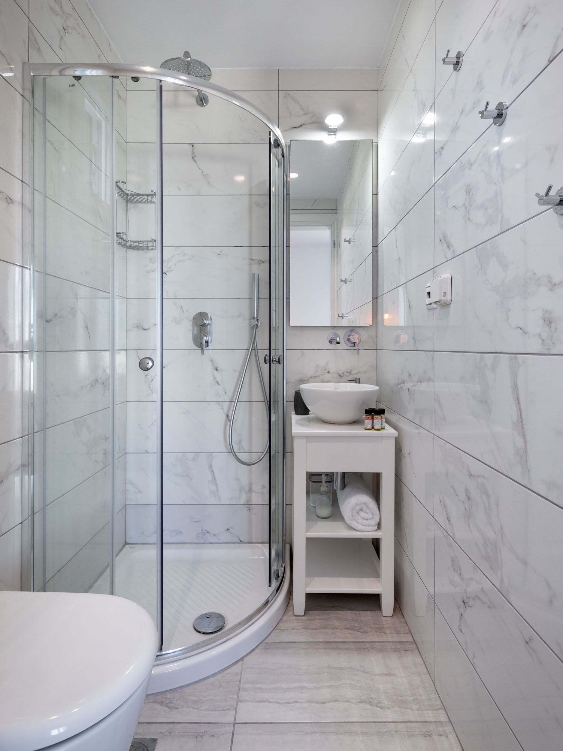 A modern bathroom with a glass-enclosed shower, a white sink, and a toilet.