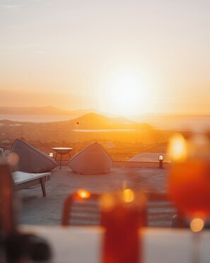 A sunset view from a rooftop terrace with seating areas and a table. - Mandilaras Village (Naxos)