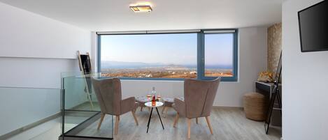 A modern room with a large window, a glass table with chairs, and a flat-screen TV on the wall.
