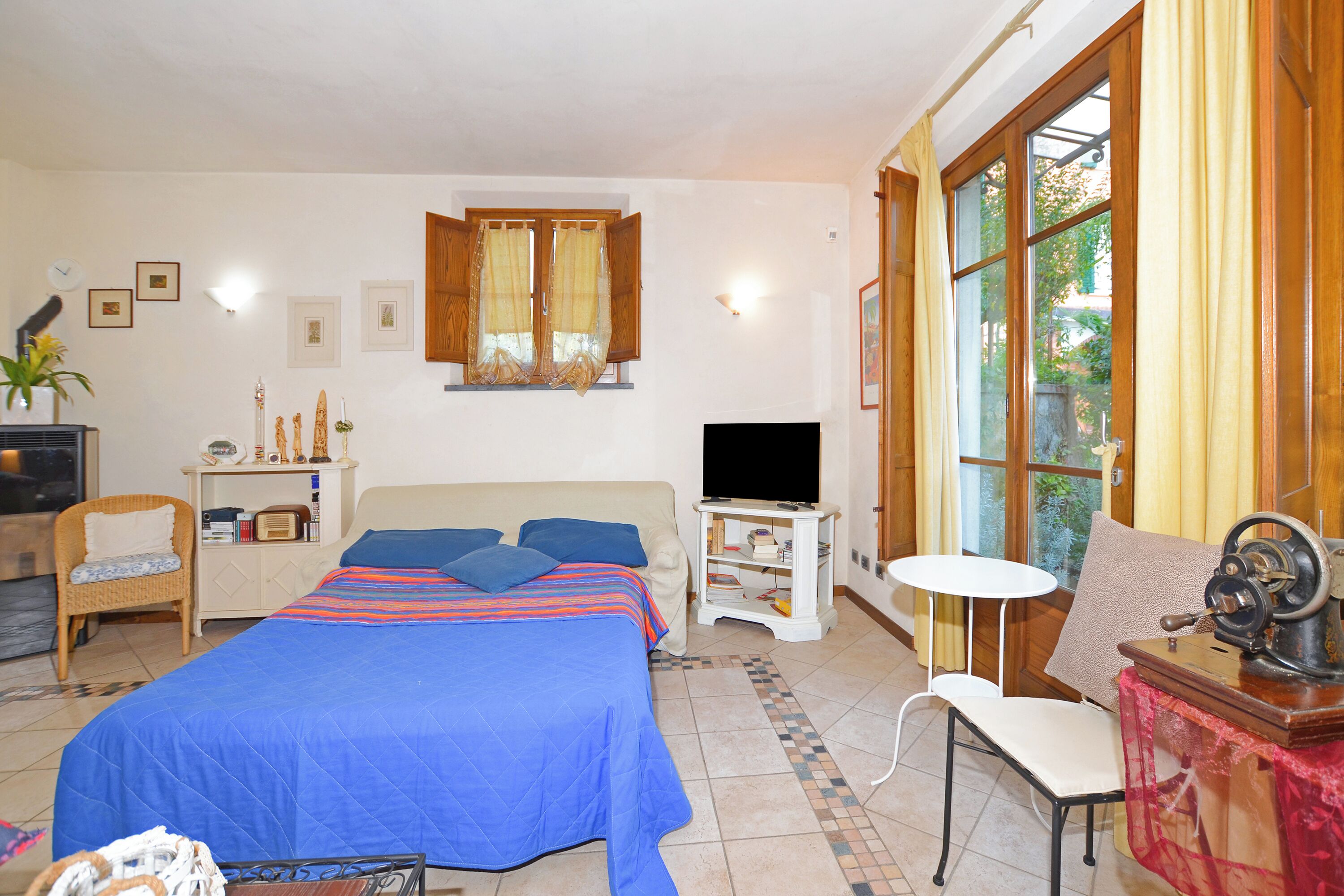 Ein Schlafzimmer mit Bett, Fernseher, Stuhl und Tisch.