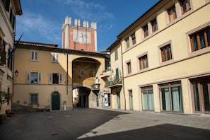 A historic street with a prominent tower, a covered passageway, and traditional buildings with balconies.