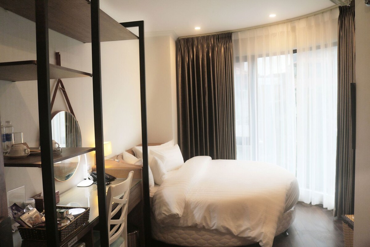 Een hotelkamer met een bed, nachtkastje, lamp en spiegel.