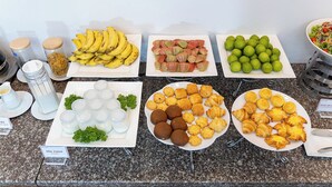 Ein reichhaltiges Buffet mit verschiedenen Speisen, darunter Bananen, Gebäck und andere Snacks.