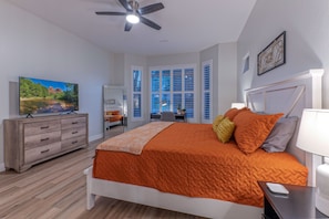 Quarto com cama, penteadeira, televisão e ventilador de teto.