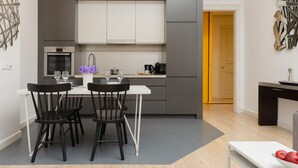 Une cuisine moderne avec un coin repas, comprenant un four encastré, une machine à café et un vase rempli de fleurs.